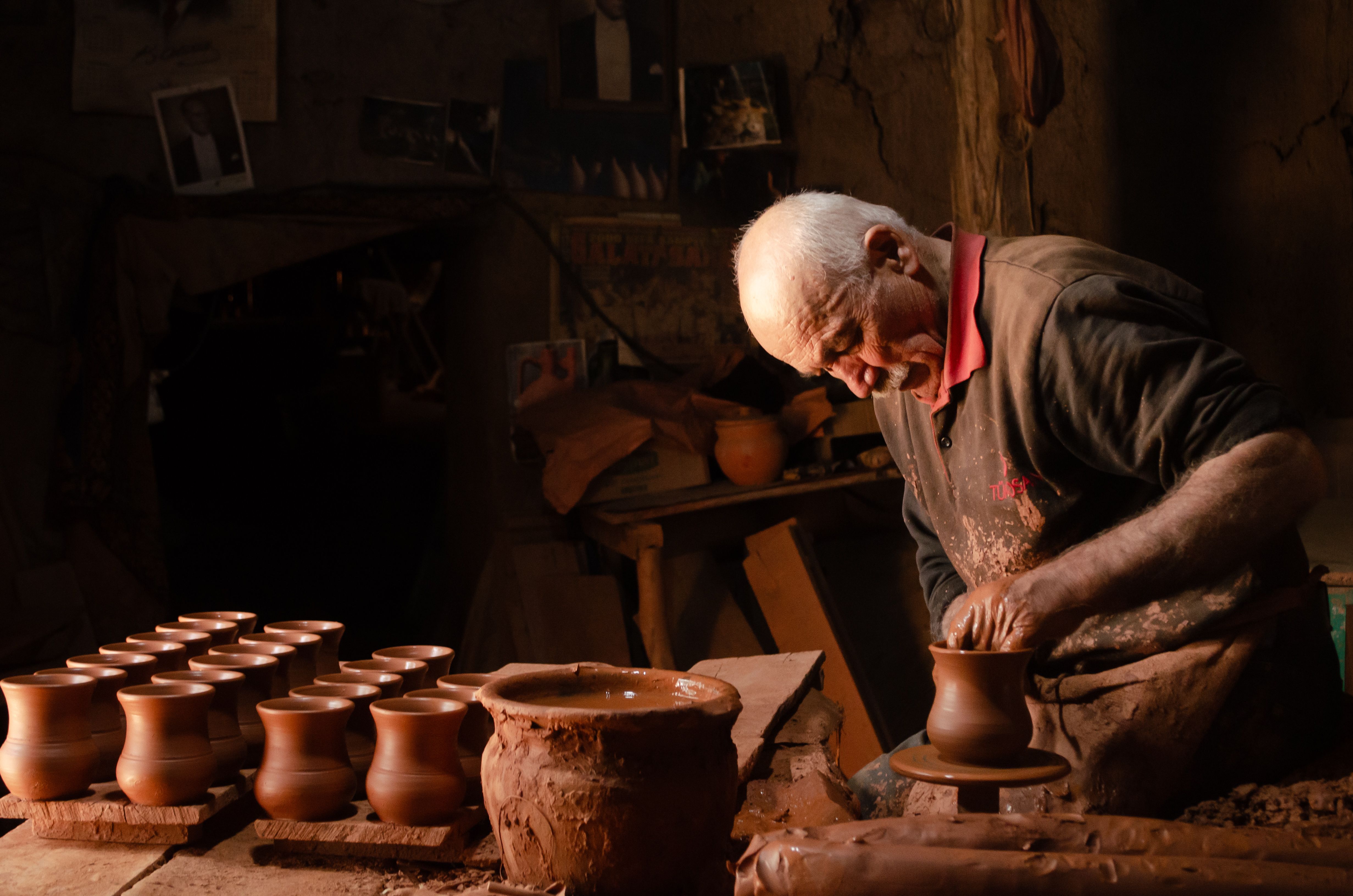 A potter shaping a cup on the wheel