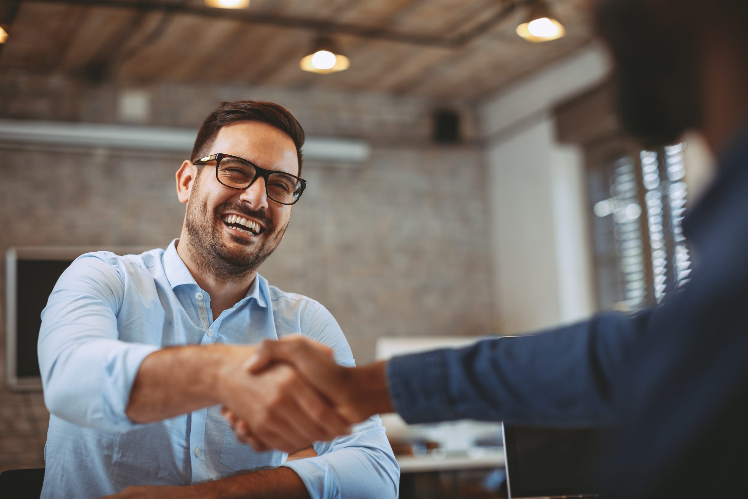A smiling man shaking hands across a table